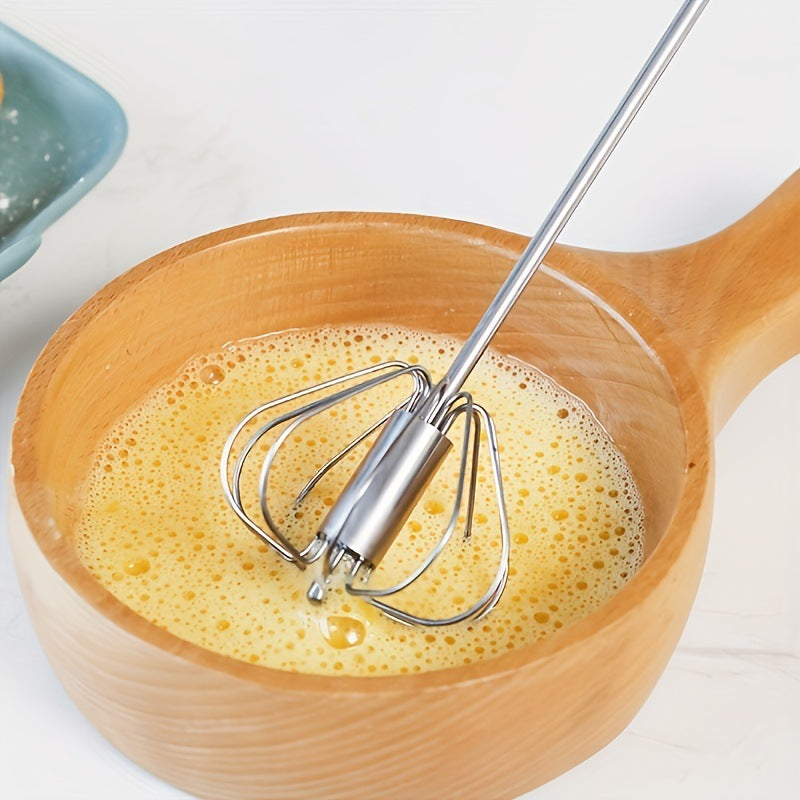 Wooden bowl with yellow mixture and metal whisk on a white background